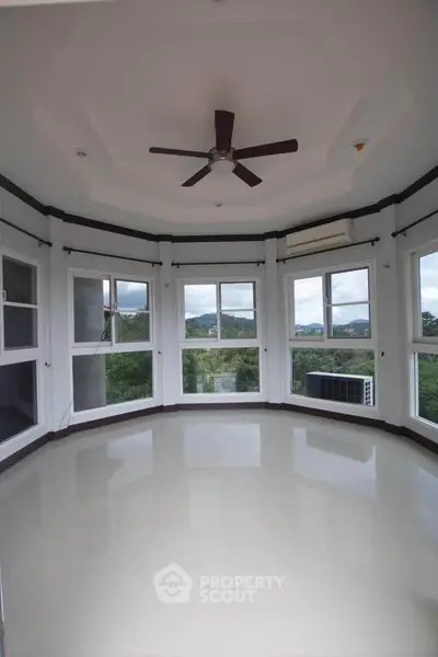 Spacious corner unit with panoramic windows and ceiling fan, offering a bright and airy atmosphere.