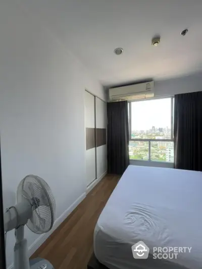 Modern bedroom with city view, featuring sleek design and ample natural light.