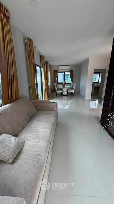 Spacious living room with elegant dining area and large windows offering natural light.