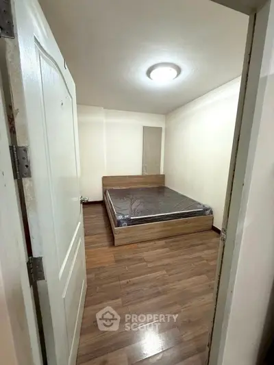 Cozy bedroom with wooden flooring and modern bed frame, perfect for restful nights.