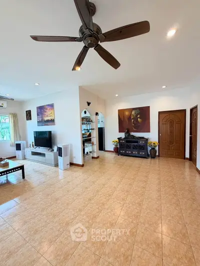 Spacious living room with ceiling fan and modern decor, perfect for family gatherings.