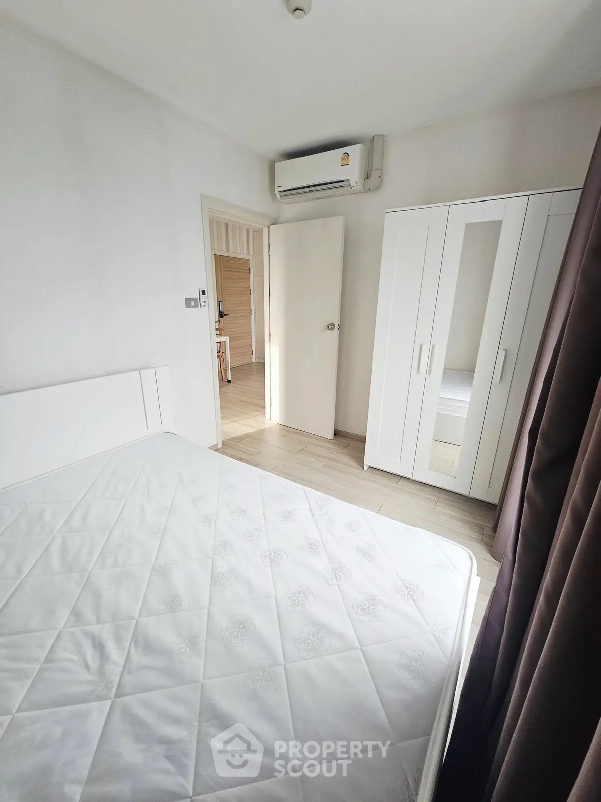 Bright bedroom with white furniture and air conditioning, perfect for a cozy living space.