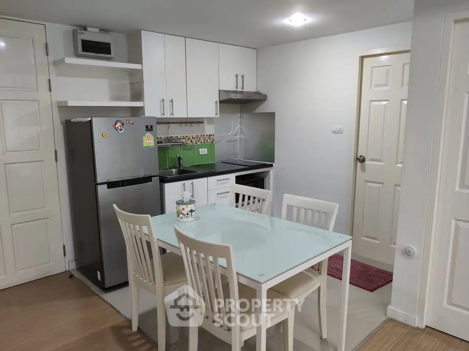Modern kitchen with dining area, featuring sleek white cabinets and a glass-top table, perfect for urban living.
