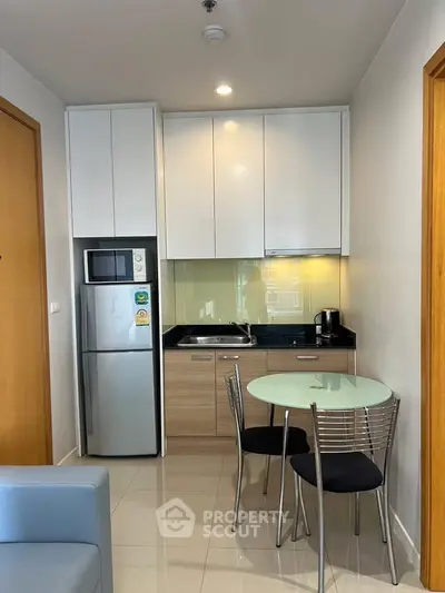 Modern compact kitchen with sleek cabinetry and dining area in cozy apartment.