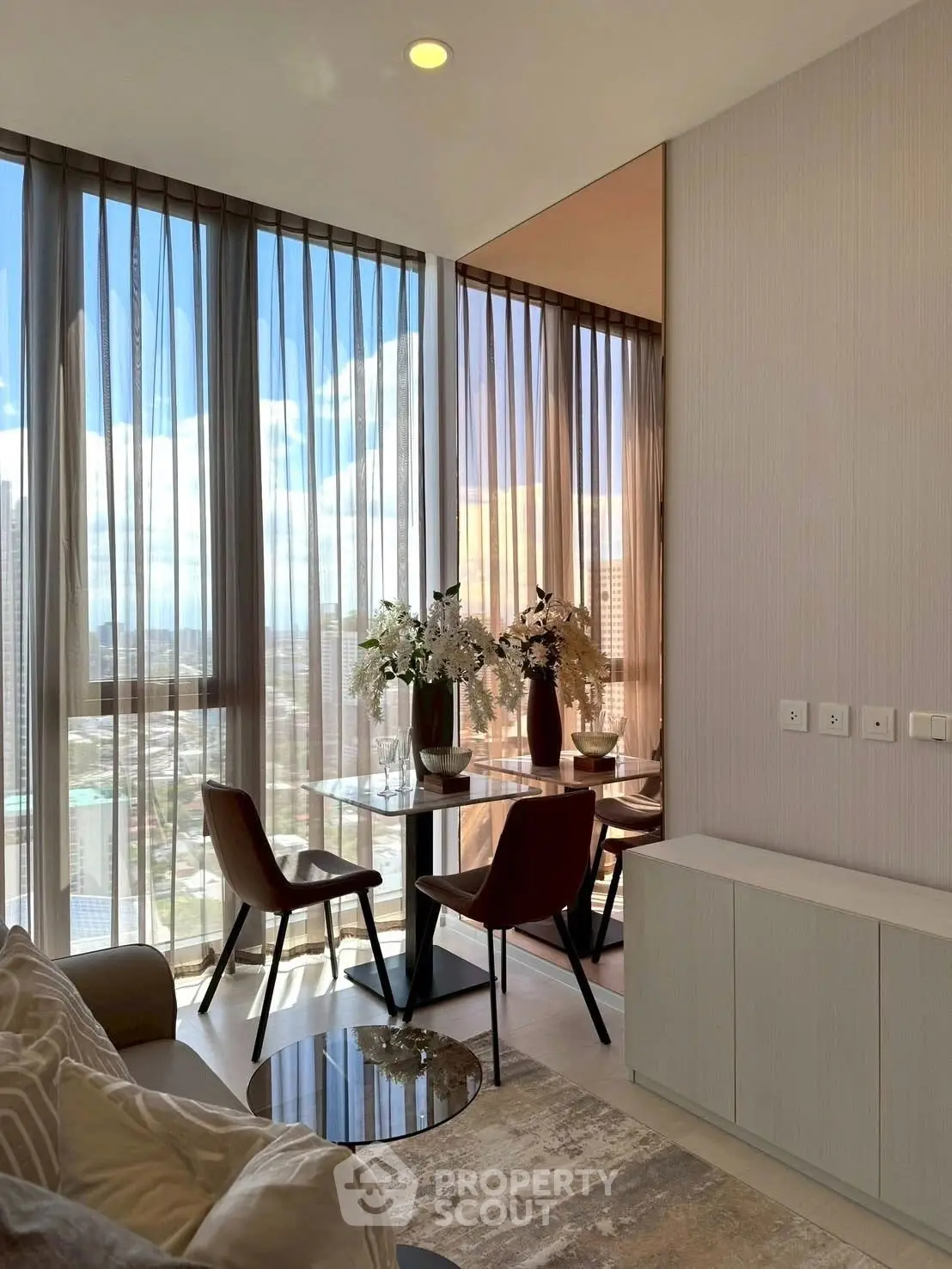 Modern living room with floor-to-ceiling windows and elegant decor in a high-rise apartment.