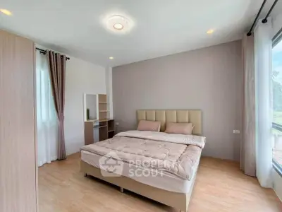 Spacious bedroom with large windows and modern furnishings in a bright, airy setting.