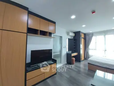 Modern studio apartment with sleek wooden cabinetry and large windows.