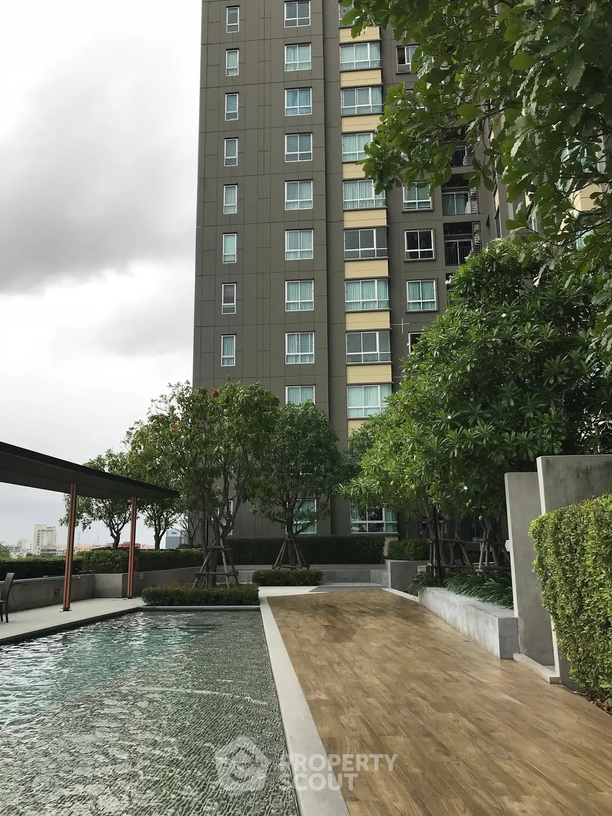 Modern high-rise building with pool and lush greenery, perfect for urban living.