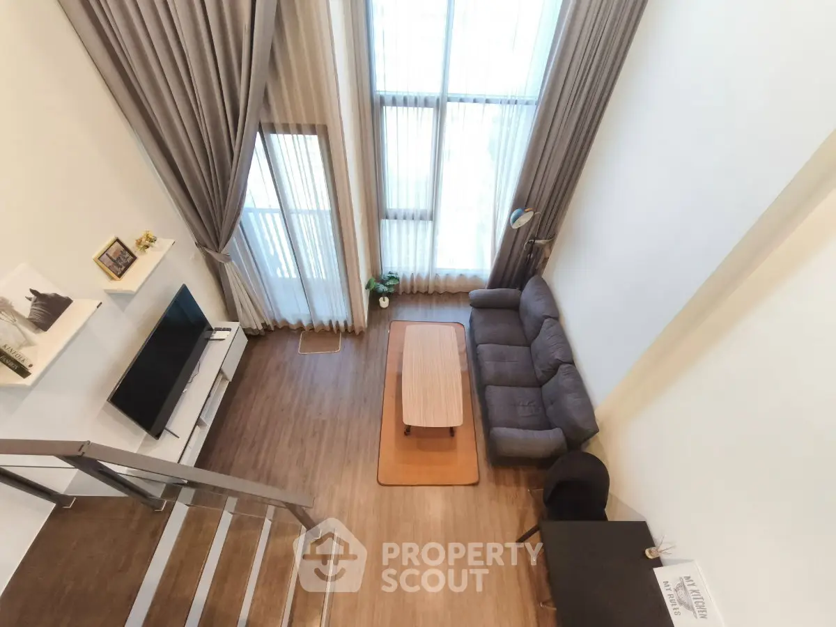 Spacious modern living room with high ceilings and large windows, featuring a cozy sofa and stylish decor.