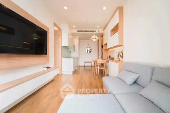 Modern living room with sleek design and open layout, featuring a large TV and cozy seating.