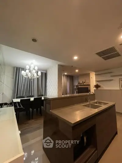 Modern kitchen with dining area featuring elegant chandelier and sleek countertops.