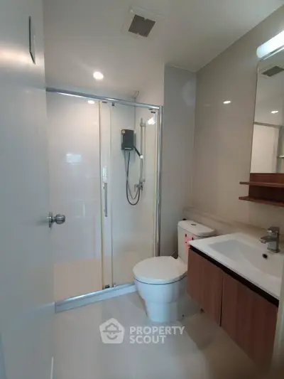 Modern bathroom with glass shower, sleek fixtures, and elegant wood accents.