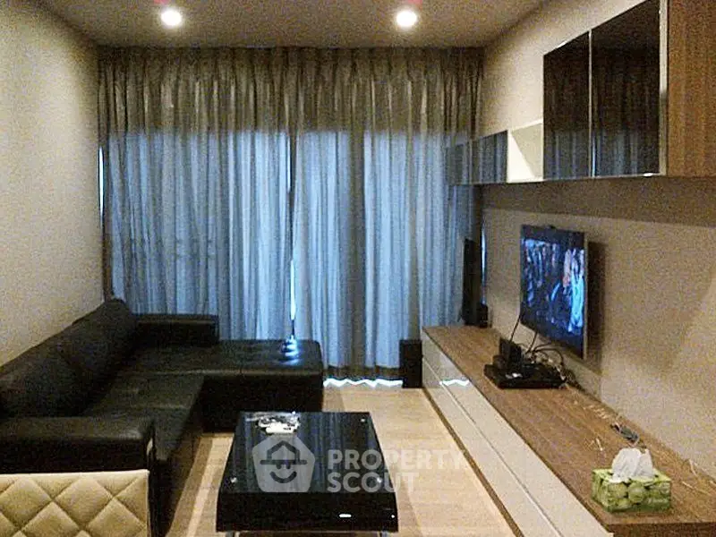 Modern living room with sleek furniture and entertainment setup, featuring a large sectional sofa and wall-mounted TV.