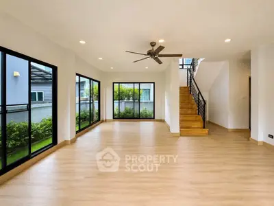 Spacious modern living room with large windows and wooden staircase