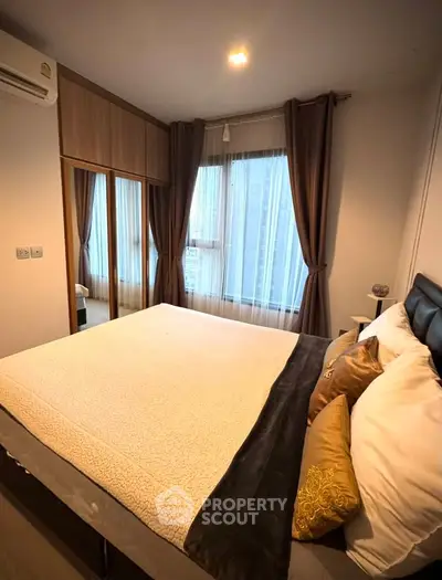 Spacious bedroom with large windows and elegant curtains in modern apartment.