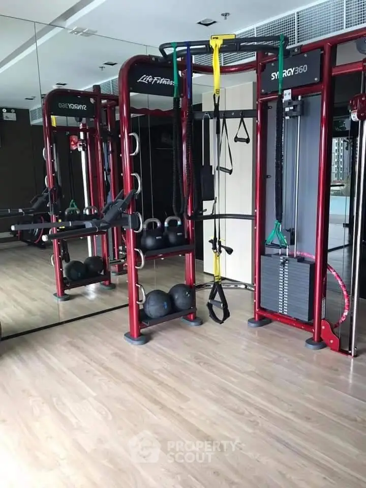 Modern gym with state-of-the-art fitness equipment and mirrored walls in luxury apartment building.