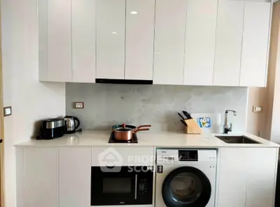 Modern kitchen with sleek white cabinets, integrated appliances, and stylish countertop.