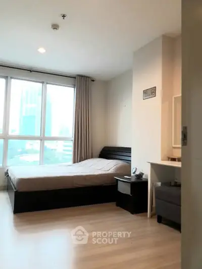 Spacious bedroom with large windows and modern furnishings in a high-rise apartment.