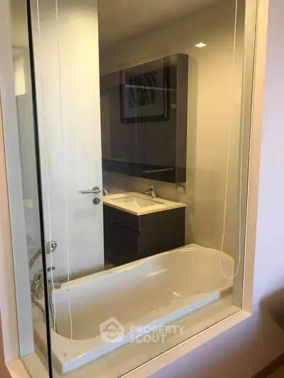 Modern bathroom with glass partition and sleek fixtures in a contemporary apartment.