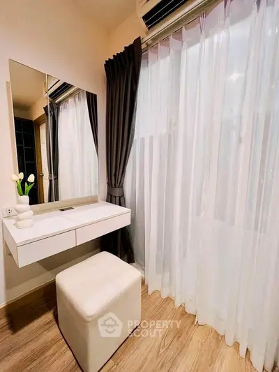 Chic modern bedroom corner with vanity, elegant curtains, and soft lighting for a cozy ambiance.