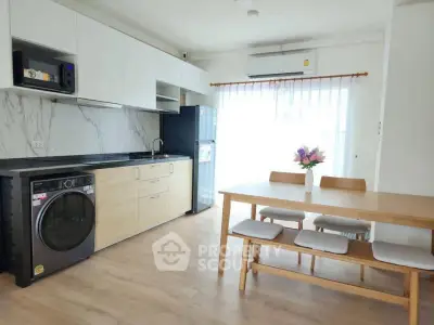 Modern kitchen with dining area, featuring sleek appliances and natural light.