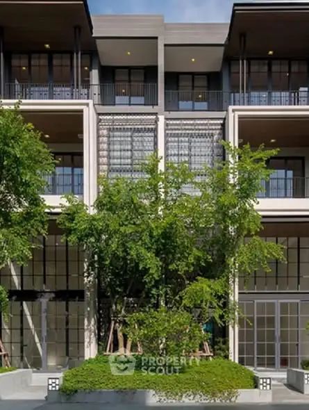Modern multi-story building with lush greenery and large windows, showcasing contemporary architectural design.