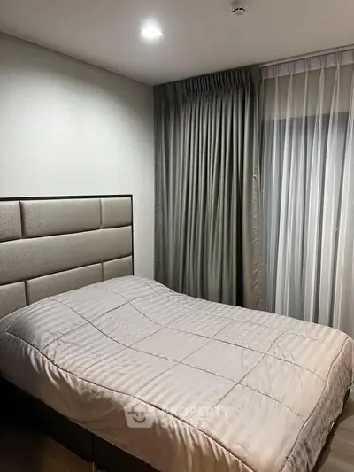 Cozy bedroom with elegant drapes and modern headboard, perfect for restful nights.