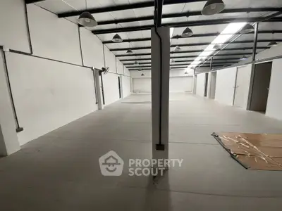 Spacious industrial warehouse interior with high ceilings and ample lighting, ideal for storage or manufacturing.
