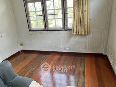 Spacious room with wooden flooring and large windows, perfect for natural light.