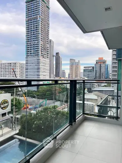Modern balcony with glass railing offering stunning cityscape views of high-rise buildings.