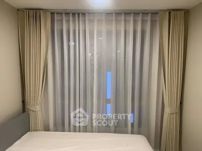 Cozy bedroom with elegant curtains and soft lighting, perfect for relaxation.