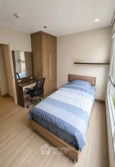 Cozy bedroom with modern furniture and ample natural light, perfect for relaxation and comfort.