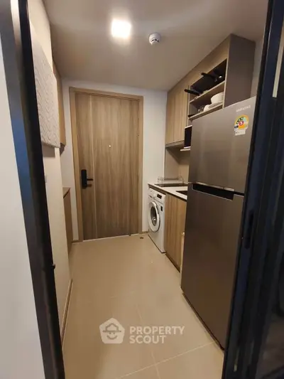 Compact kitchen with modern appliances including fridge and washing machine, sleek cabinetry, and stylish design.