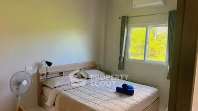 Cozy bedroom with large window and air conditioning, perfect for relaxation.