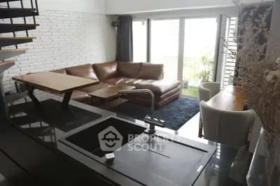 Modern living room with sleek kitchen island and leather sofa, featuring a balcony view.