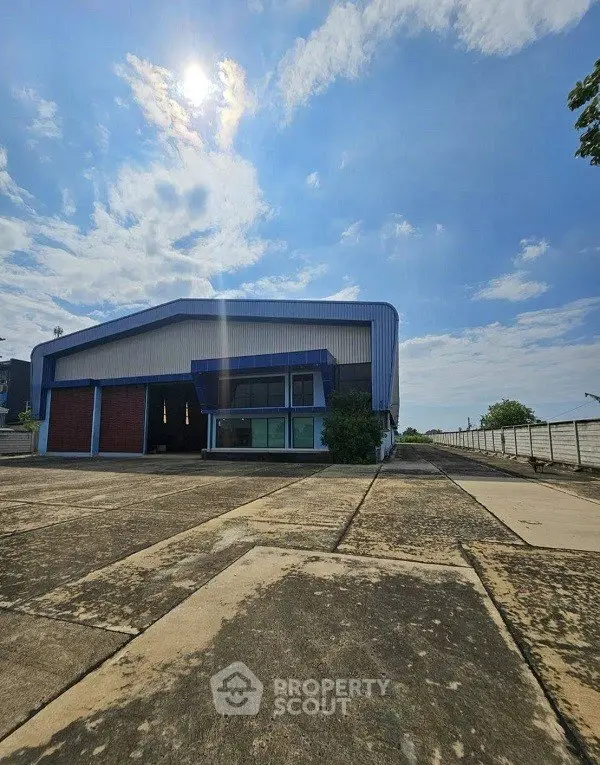 Spacious industrial warehouse with ample outdoor space under a clear blue sky.