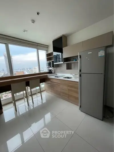 Modern kitchen with city view, featuring sleek cabinetry and large windows.