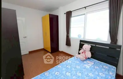 Cozy bedroom with wooden flooring and large window for natural light.