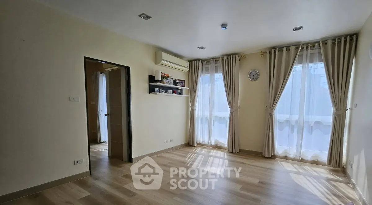 Spacious empty room with wooden flooring and large windows, perfect for customization.