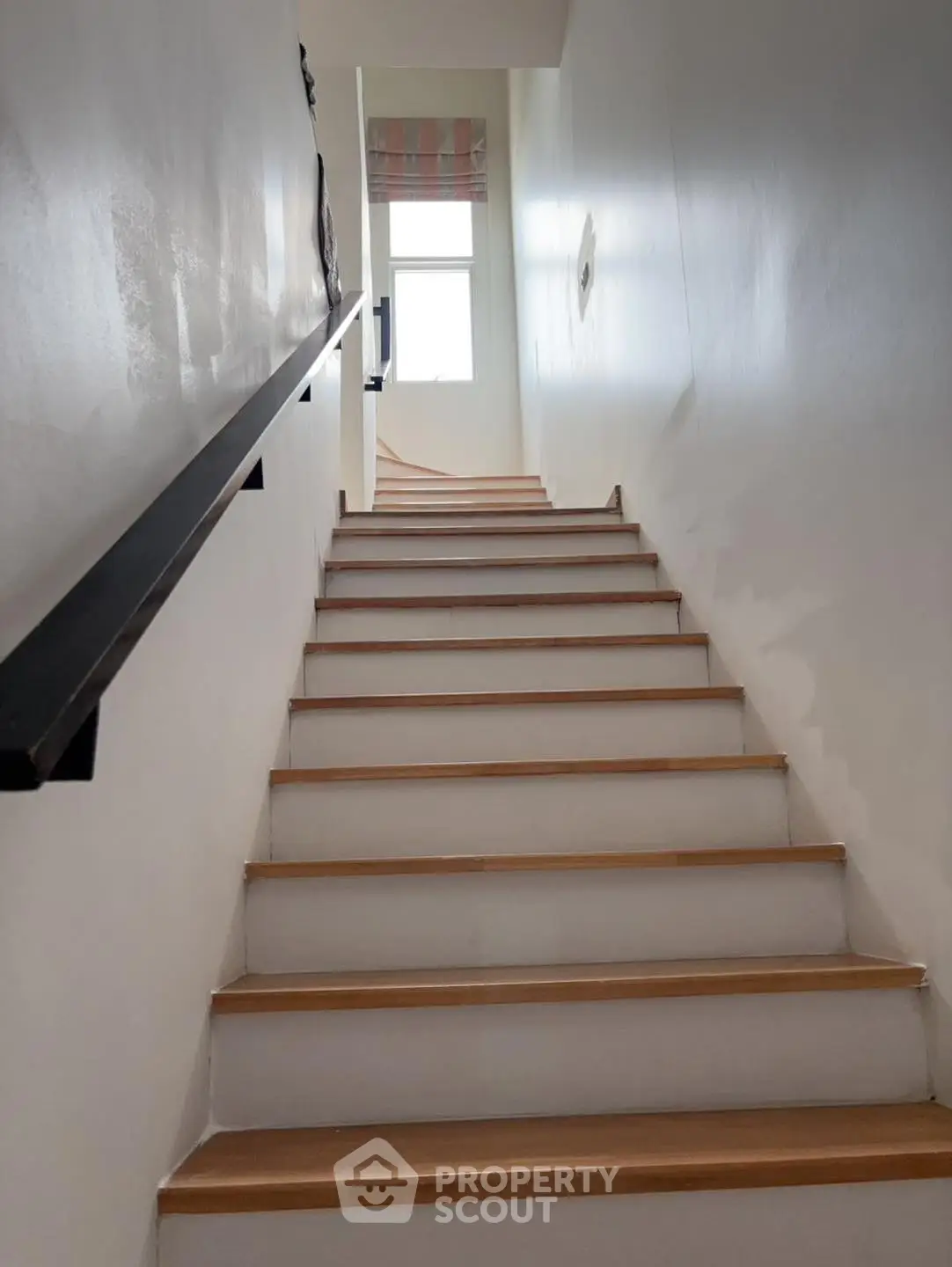 Modern staircase with wooden steps and sleek handrail in a bright interior space.