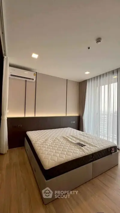 Modern bedroom with large window and stylish decor in a high-rise apartment.