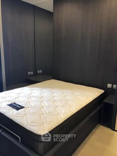 Modern bedroom with sleek dark wood paneling and comfortable mattress.