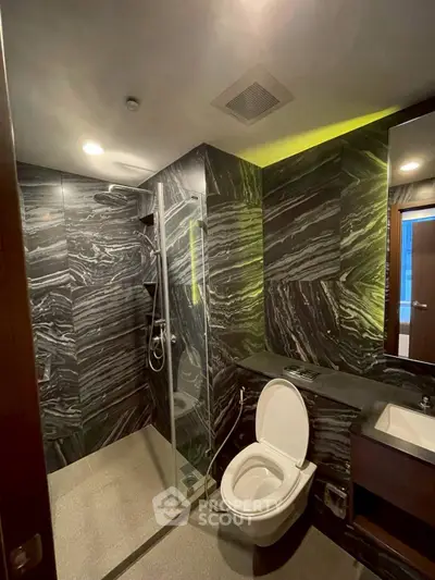 Luxurious modern bathroom with sleek black marble design and glass shower enclosure.