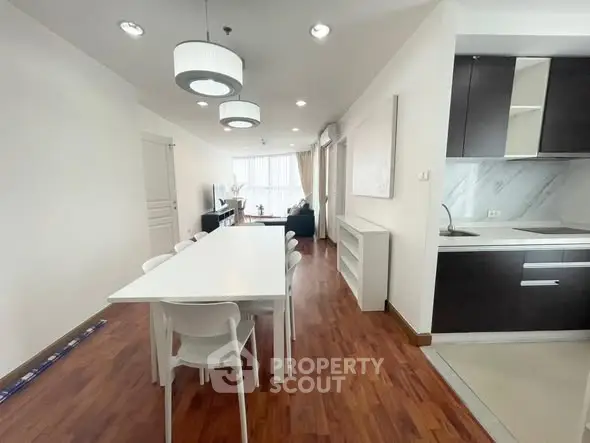 Spacious modern dining area with open kitchen and stylish lighting in a contemporary apartment.