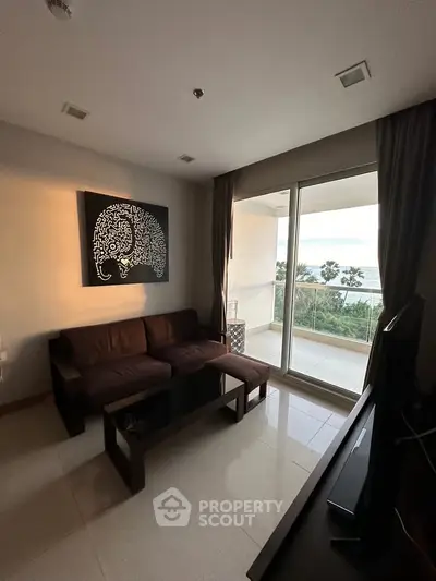 Modern living room with balcony and ocean view, featuring stylish decor and natural light.