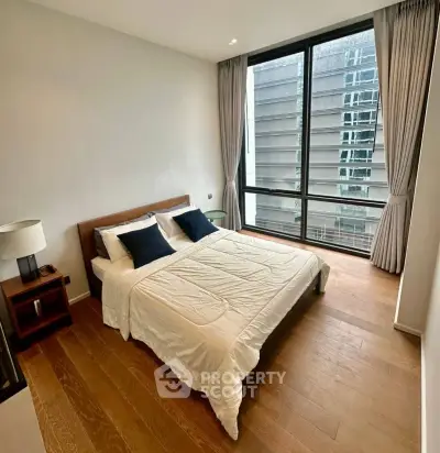 Modern bedroom with large window and wooden flooring in urban apartment