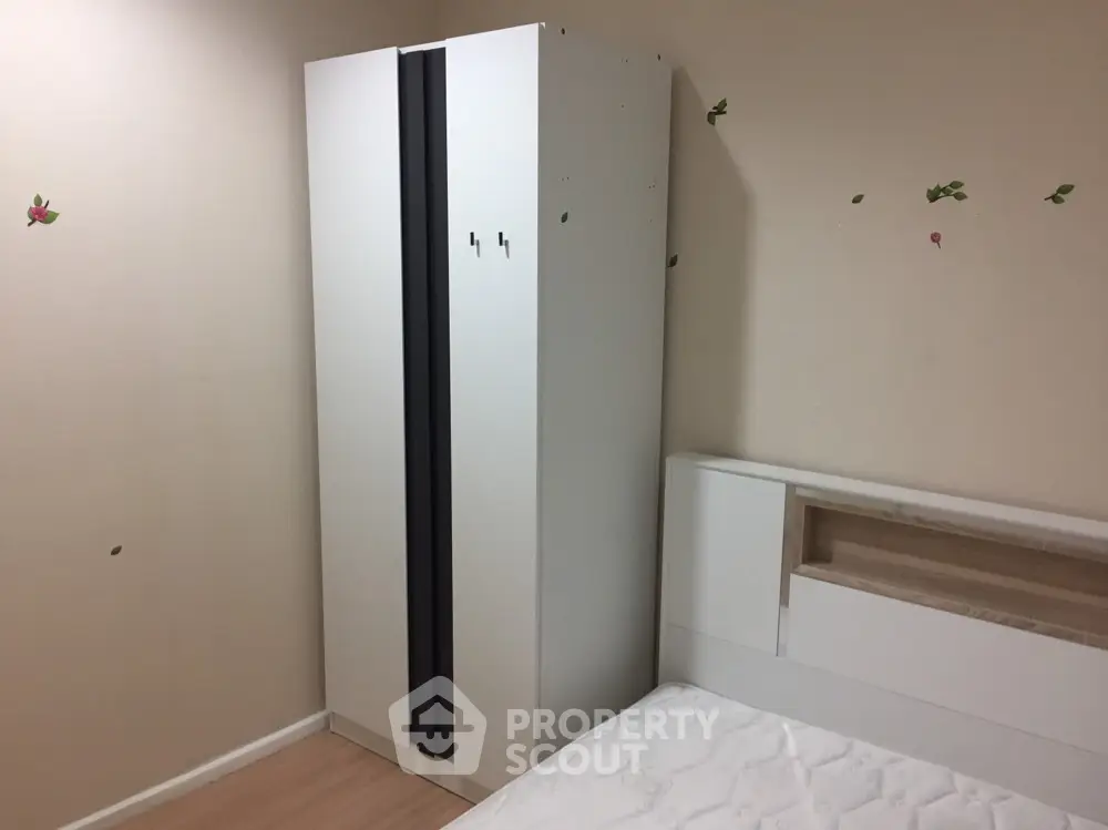 Cozy bedroom with modern wardrobe and comfortable bed, adorned with playful butterfly stickers, perfect for restful nights in a compact urban home.