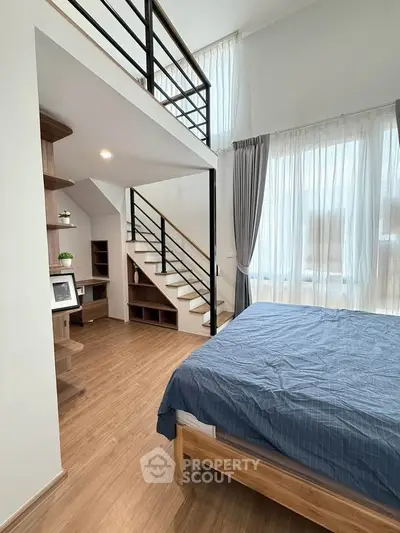 Modern loft bedroom with mezzanine and large windows, featuring stylish wooden flooring and contemporary design.