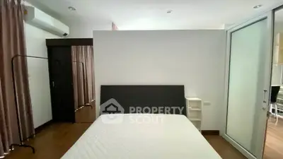 Spacious bedroom with modern design and ample natural light, featuring a comfortable bed and stylish decor.