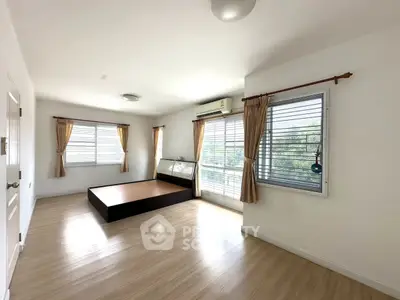 Spacious bedroom with large windows and wooden flooring, ideal for natural light lovers.